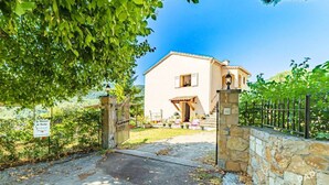 A two-story building with a stone entrance gate, a small porch, and a clear sky. - Apartment for 6 People (Le Bar-sur-Loup)