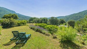 A grassy outdoor area with two green chairs, surrounded by lush greenery and hills in the background. - Apartment for 6 People (Le Bar-sur-Loup)