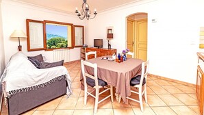 A cozy room with a bed, a dining table with chairs, a TV, and a window with a view. - Apartment for 6 People (Le Bar-sur-Loup)