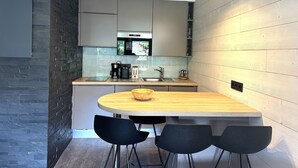 Eine moderne Küche mit einer zentralen Kochinsel, schwarzen Stühlen und einem Holztisch.