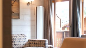 Ein Zimmer mit einem gestreiften Sofa, einem Sessel, einer Lampe und einem fenster mit Vorhängen.