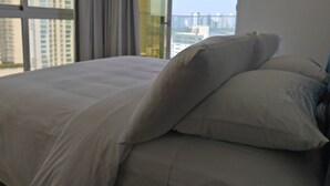 A hotel room with a bed, a window with curtains, and a view of buildings. - Brilliant 3-bedroom apartment with AC in vibrant Panamá (Panamá)