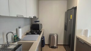 A compact kitchen with a gas stove, microwave, and stainless steel refrigerator. - Brilliant 3-bedroom apartment with AC in vibrant Panamá (Panamá)