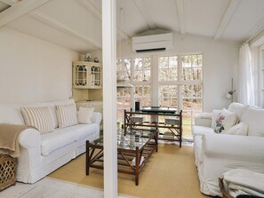 A room with a white sofa, a glass coffee table, and a cabinet with glass doors. - 4 Star Holiday Home in Vig (Vig)