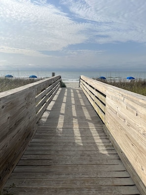 A wooden boardwalk leading to the beach with a clear view of the ocean. - 3-bedroom Myrtle beach house just a short walk to beach. Includes golf cart. (Myrtle Beach)
