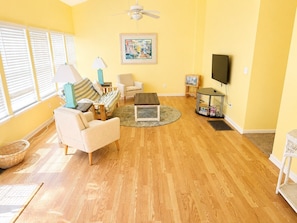 A living room with a sofa, armchairs, a coffee table, a TV, and a ceiling fan. - 3-bedroom Myrtle beach house just a short walk to beach. Includes golf cart. (Myrtle Beach)