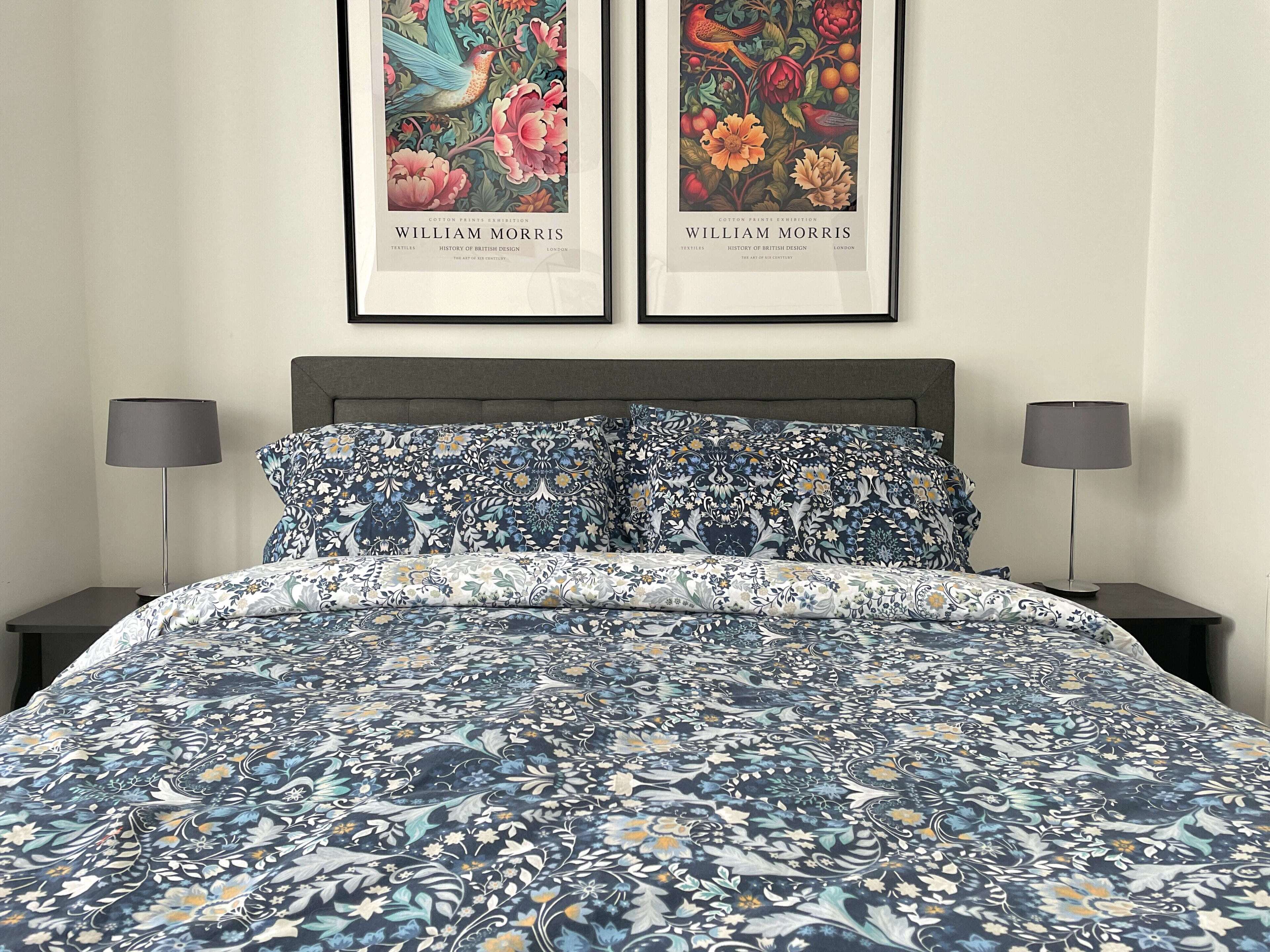 A bedroom with a bed, two nightstands, and two framed artworks on the wall.