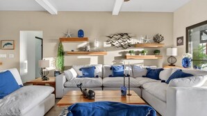 Ein modernes Wohnzimmer mit einer Eckcouch, einem Holztisch und Dekoration auf Regalen.