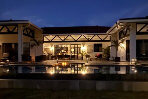 Une maison moderne dotée d’une piscine, d’un espace salon extérieur et d’un patio.
