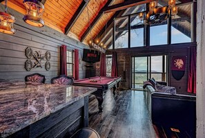 Ein gemütliches Zimmer mit Billardtisch, bequemen Sitzgelegenheiten und einem großen Fenster mit Blick.