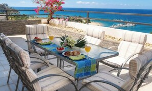 A dining table with chairs, a flower arrangement, and food items.