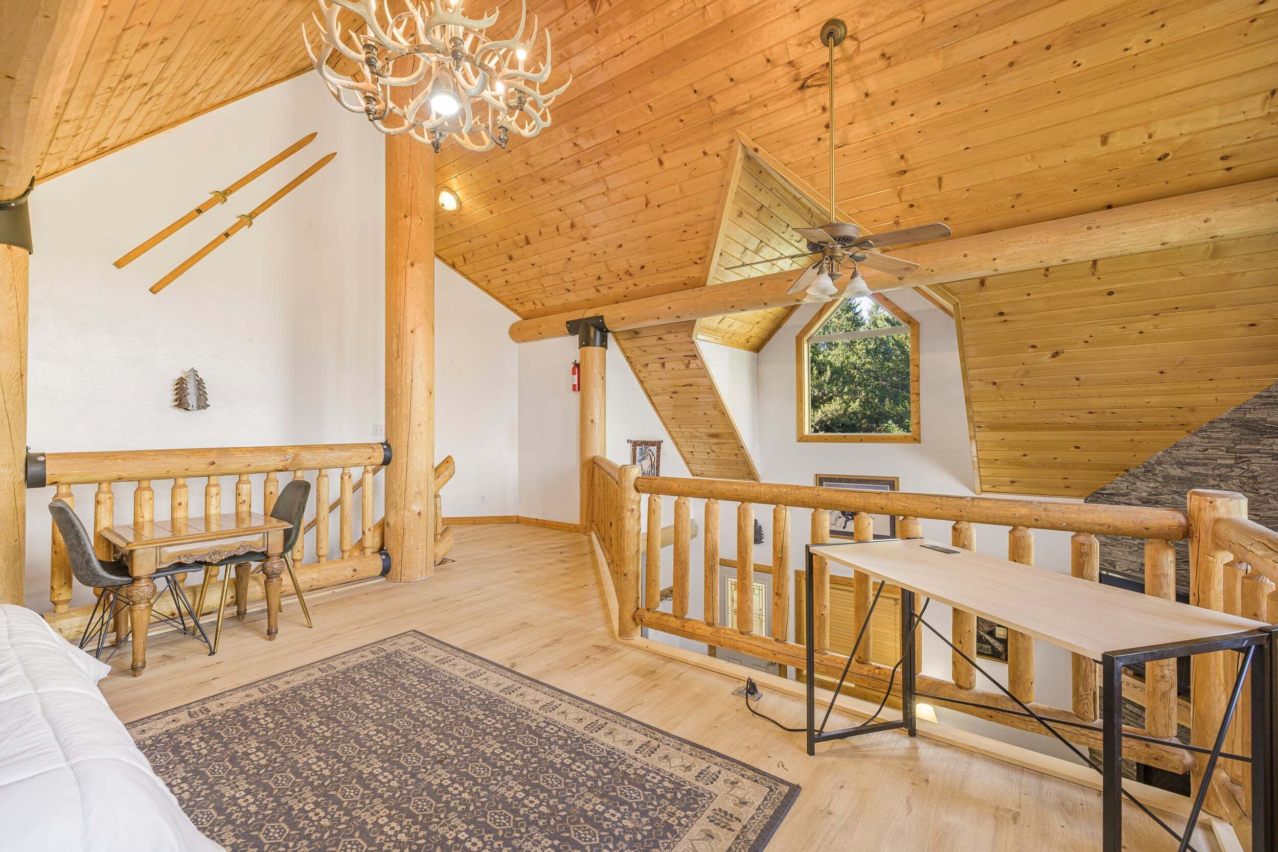 Un interior de madera con una zona de comedor, una escalera y un candelabro.