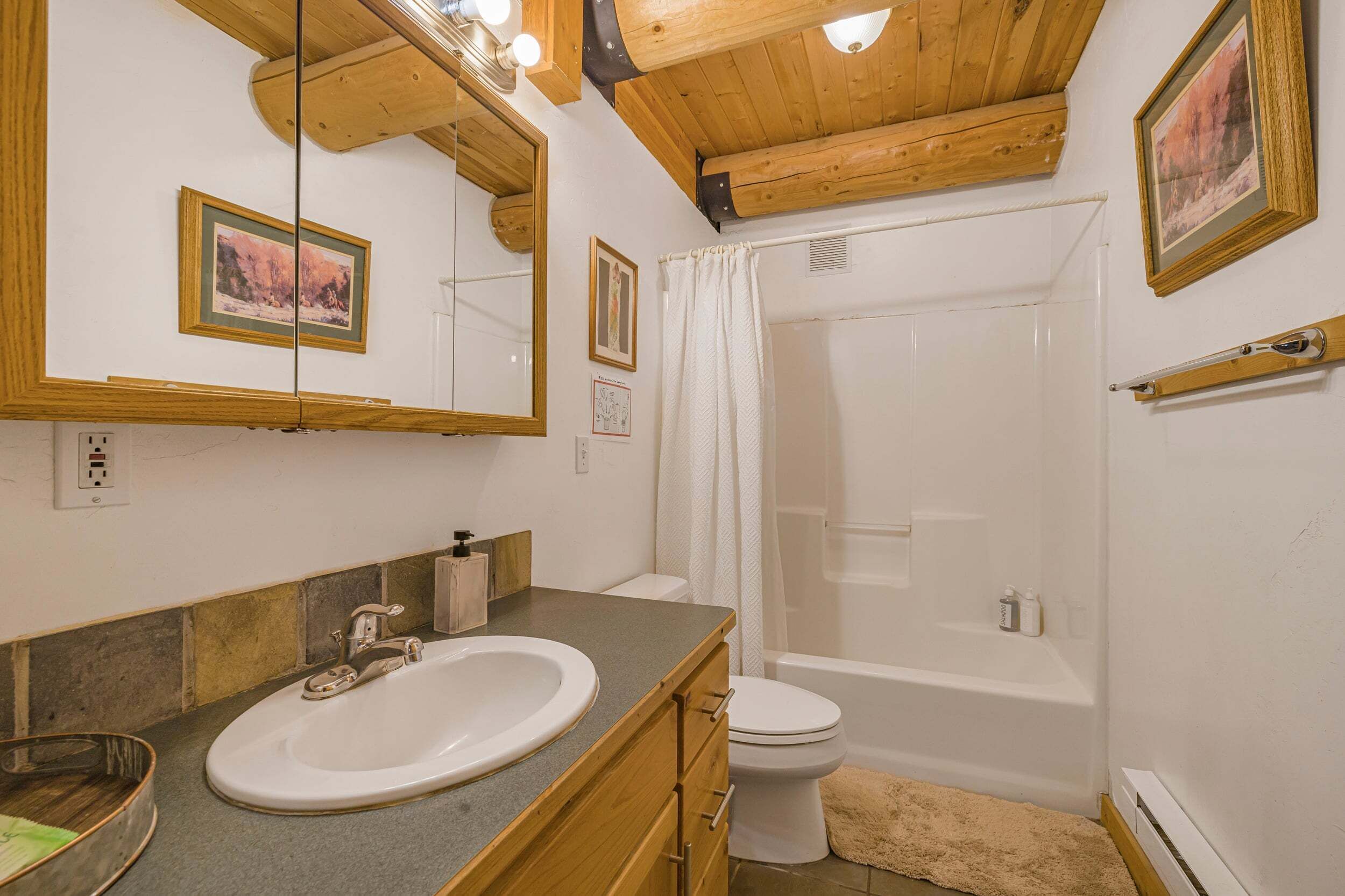 A bathroom with a wooden ceiling, a sink, a toilet, and a bathtub.