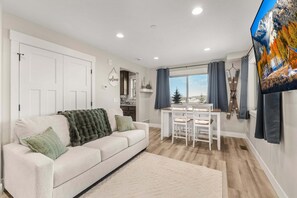 A living room with a sofa, a dining table, and a TV. - Victor Headwall (Victor)