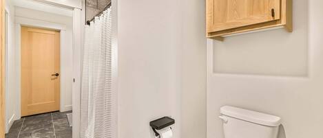 Une salle de bain avec des toilettes, un rideau de douche et un meuble en bois.