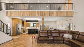 A spacious living area with a large brown leather sofa, a wooden dining table, and a kitchen in the background. - Checkmate (Island Park)