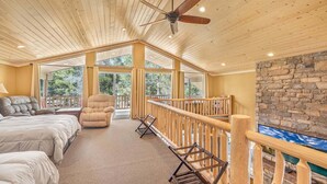 A spacious room with a high ceiling, a ceiling fan, a bed, a chair, a balcony, and a stone wall. - Jensen Pines (Island Park)