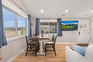 A dining area with a table and chairs, a television on the wall, and a view of the outdoors. - Victor Traverse (Victor)