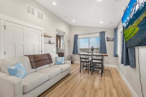 A living room with a sofa, a dining table, and a TV. - Victor Traverse (Victor)