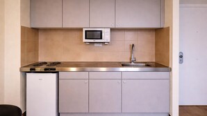 Une cuisine compacte équipée d’un four à micro-ondes, d’un évier et d’un petit réfrigérateur.
