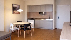 Une cuisine compacte équipée d’un four à micro-ondes, d’un évier et d’un coin repas avec des chaises et une table.