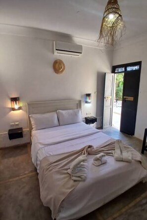 A bedroom with a bed, bedside tables, an air conditioning unit, a wall-mounted TV, and a door leading outside. - Villa Marine Privée (heated pool, 5 bedrooms) (Marrakech)