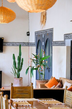 A dining area with a table, chairs, a hanging basket, and a door with decorative trim. - Villa Marine Privée (heated pool, 5 bedrooms) (Marrakech)