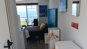 Ein Hotelzimmer mit Bett, Schreibtisch, Stuhl, Kleiderschrank, Spiegel und Meerblick.