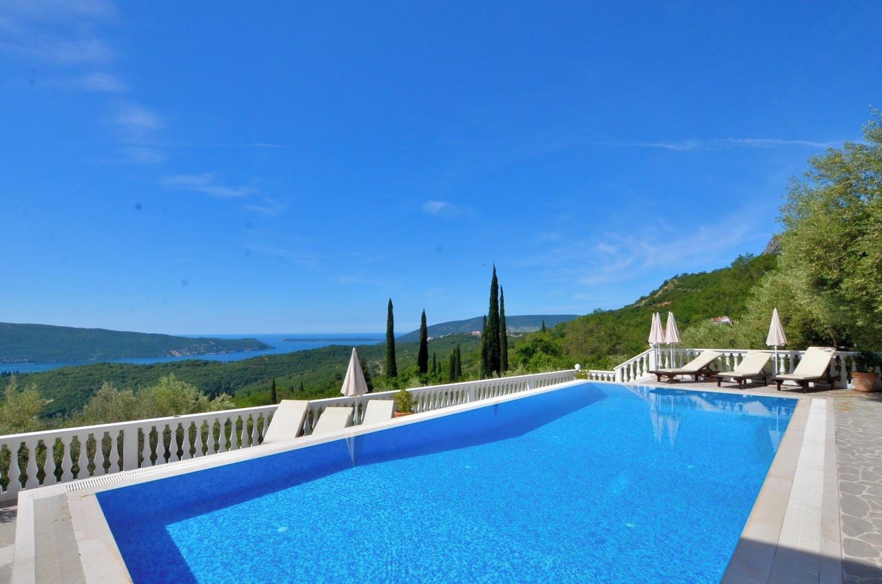A swimming pool with a view of a mountainous landscape and the sea.