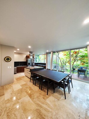 A modern kitchen with a dining area, large windows, and a view of trees. - Luxurious Villa in Amapas, Zona Romantica, Malecon! (Puerto Vallarta)