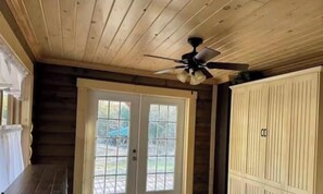 Un intérieur en bois avec un ventilateur de plafond, une porte à panneaux de verre et une grande armoire blanche.