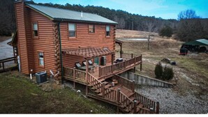 A two-story log cabin with a deck, surrounded by a grassy area and trees. - Cabin in the Shawnee National Forest (Eddyville)