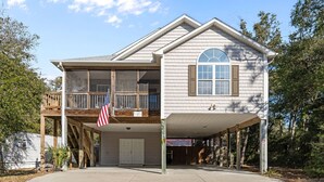 Een huis met twee verdiepingen, een overdekte garage, een balkon en een Amerikaanse vlag.