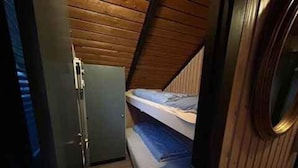 A compact room with a bunk bed, a small refrigerator, and a wooden ceiling. - 4 Star Holiday Home in Fjerritslev (Fjerritslev)