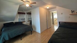 A bedroom with two beds, a ceiling fan, a window with curtains, and a door leading to another room. - Serene 2-bedroom lake house in welcoming Unity, perfect for relaxing stays (Unity)