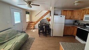 A compact living space with a kitchenette, a dining area, a staircase, and a bed. - Serene 2-bedroom lake house in welcoming Unity, perfect for relaxing stays (Unity)