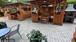 A patio with wooden pergolas, outdoor seating, and a barbecue area. - Willa Balticus Władysławowo (Władysławowo)