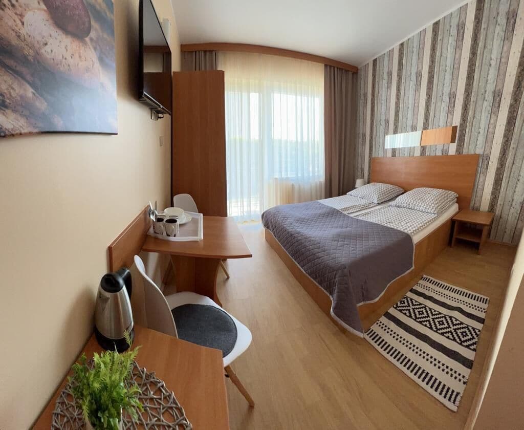 Ein Hotelzimmer mit Bett, Schreibtisch mit Stuhl, einer Kaffeemaschine und einer Pflanze.