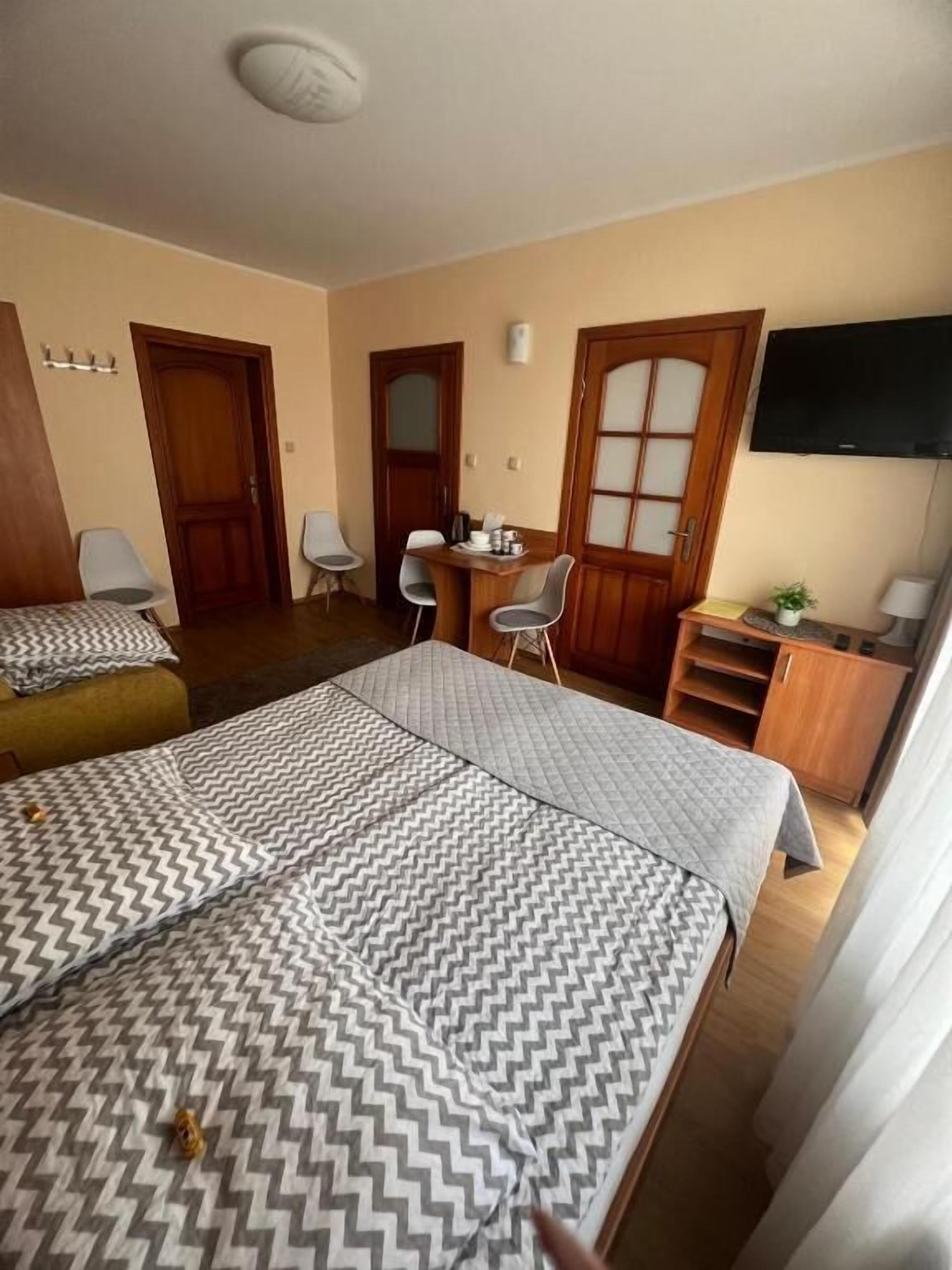 Habitación de hotel con cama, escritorio con sillas, televisor y armario.