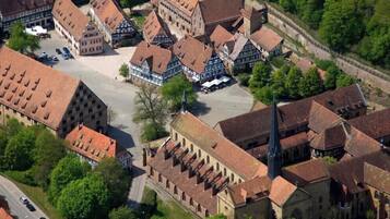 An aerial view of a historic town with traditional half-timbered buildings, a central square, and a church with a prominent steeple.