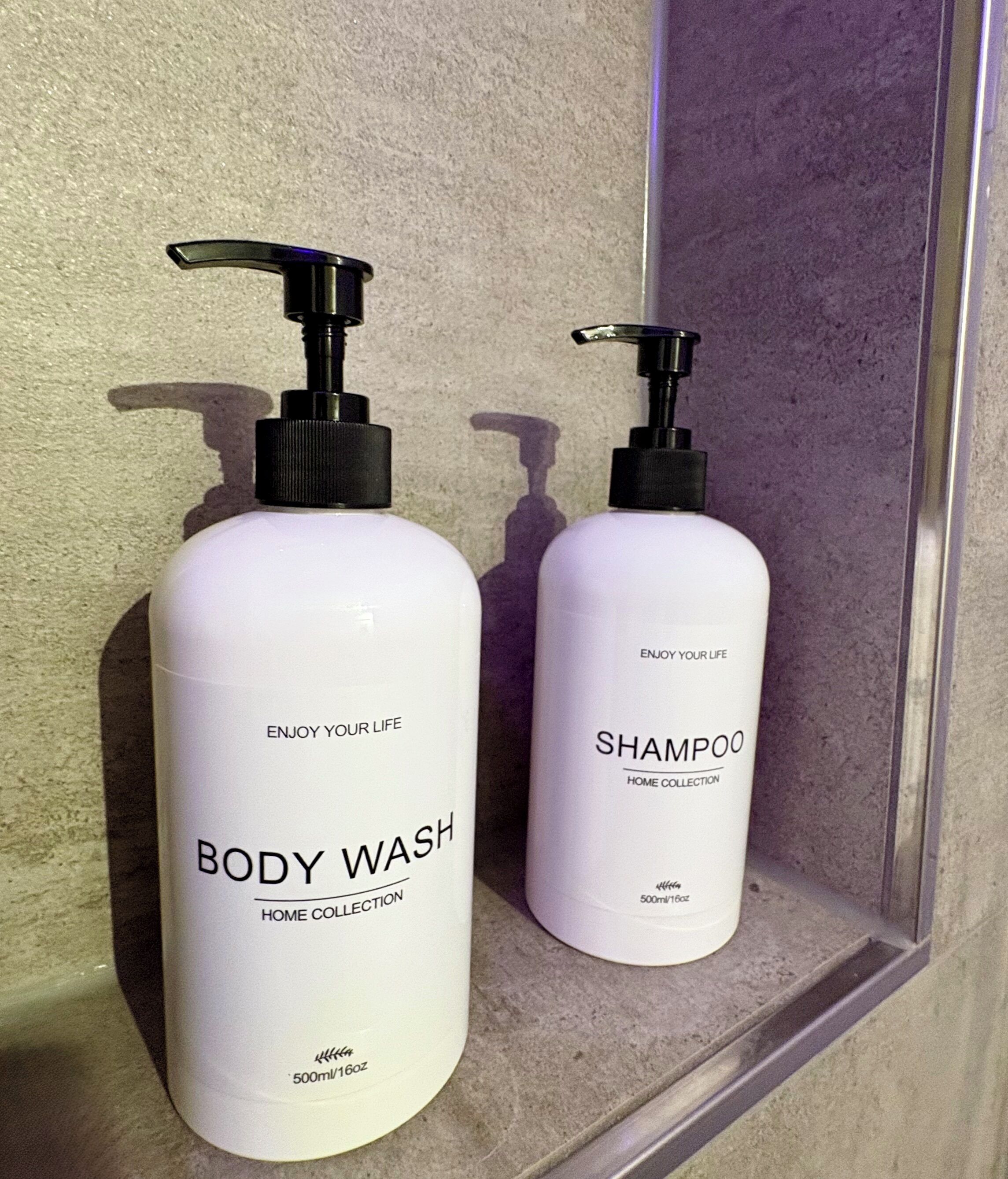 Kaksi pulloa vartalopesua ja shampoota kylpyhuoneessa.