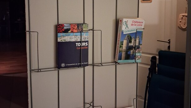 A wall-mounted rack with travel brochures and maps. - First floor room in a town house. (La Riche)