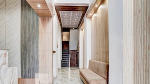A hallway with a marble floor, a wooden bench, and a staircase leading to another room. - Townhouse Railway Road Katrathe Amro (Reasi)