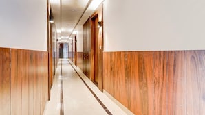 A long, narrow hallway with wooden paneling on the walls and a marble floor. - Townhouse Railway Road Katrathe Amro (Reasi)