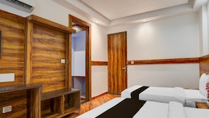 A hotel room with a wooden accent wall, a bed with white bedding, a bench, and a wardrobe. - Townhouse Railway Road Katrathe Amro (Reasi)