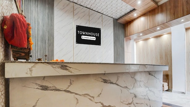 A reception desk with a marble top, a sign indicating it's a company-serviced townhouse, and a wooden interior. - Townhouse Railway Road Katrathe Amro (Reasi)