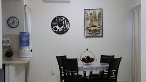 A dining area with a table, chairs, a water dispenser, a clock, and wall decorations.