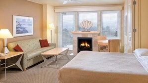 Ein Hotelzimmer mit Bett, Sofa, Tisch, Kamin und Blick auf die Stadt durch große Fenster.