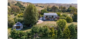 Una casa con un amplio jardín delantero, rodeada de árboles y colinas.