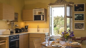 Een keuken met houten kastjes, een magnetron, een koffiezetapparaat en een eethoek met een tafel en stoelen.